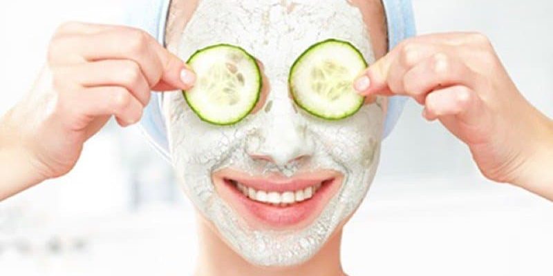 Funny young girl with a mask for skin face and cucumbers