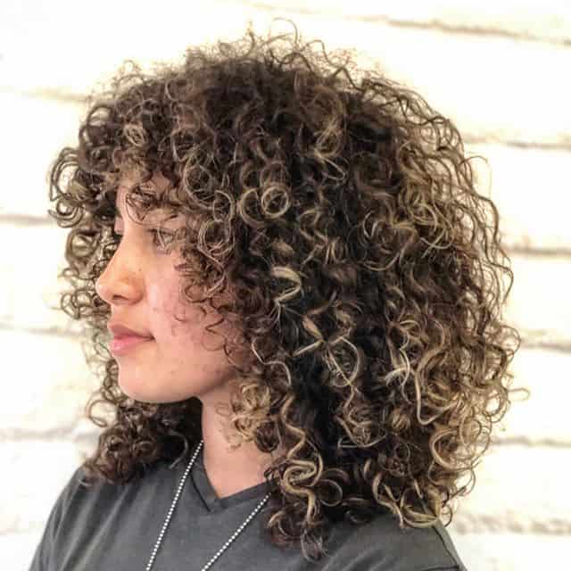 Tight Bouncy Curls With Bangs And Blonde Highlights