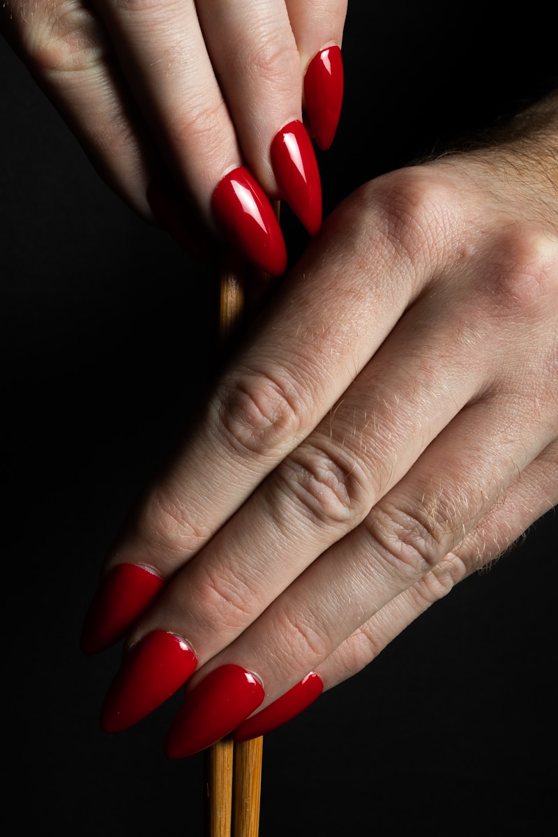 a woman's hand with red nail polish holding a stick