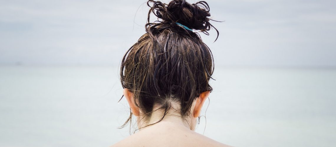 woman facing seashore with wet hair