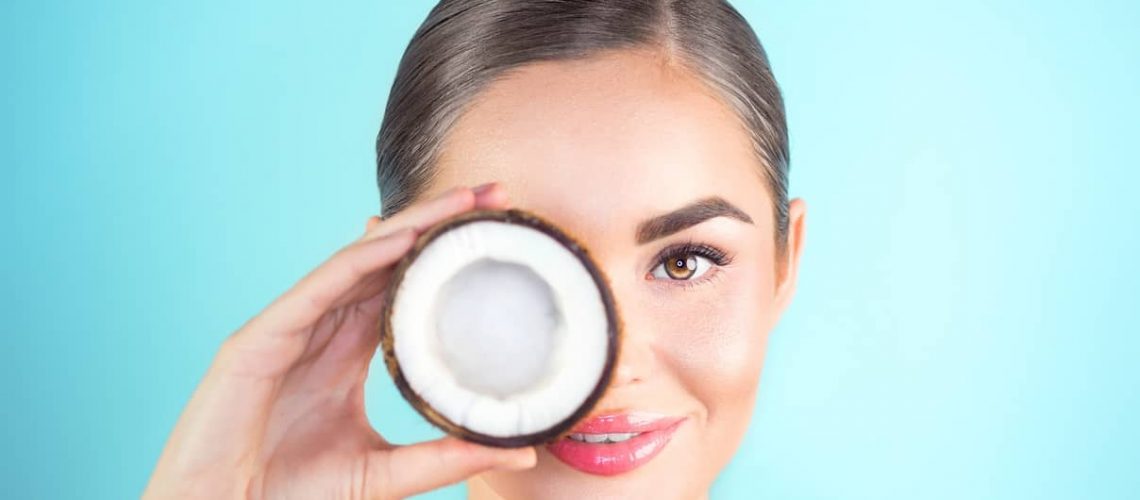 Beauty Woman with coconut Portrait. Spa model girl holding coco nut and smiling. Pretty young brunette woman face. Skin care. Youth. Beautiful Fashion Model Girl Face. Perfect Skin. Health care