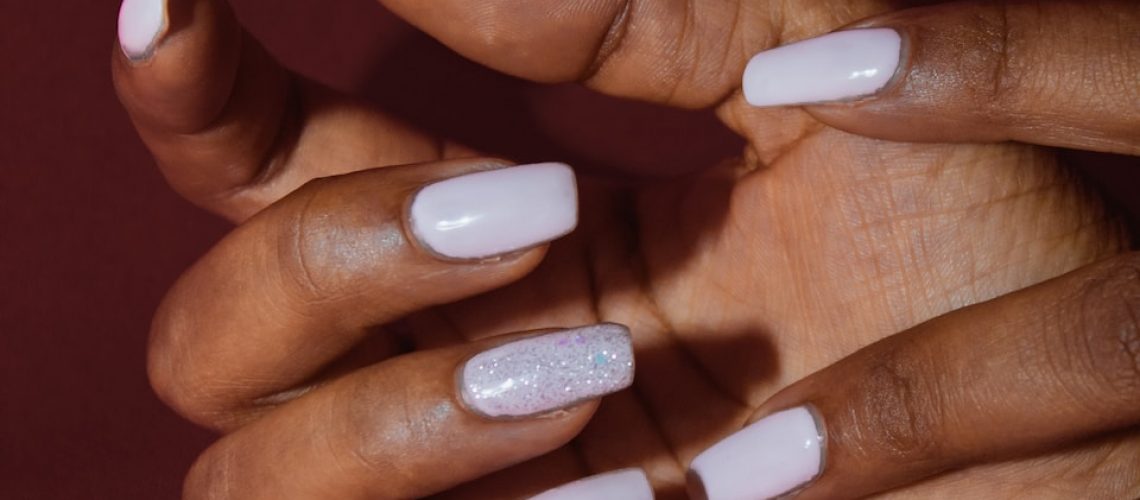 a woman's hands with white nail polish on them