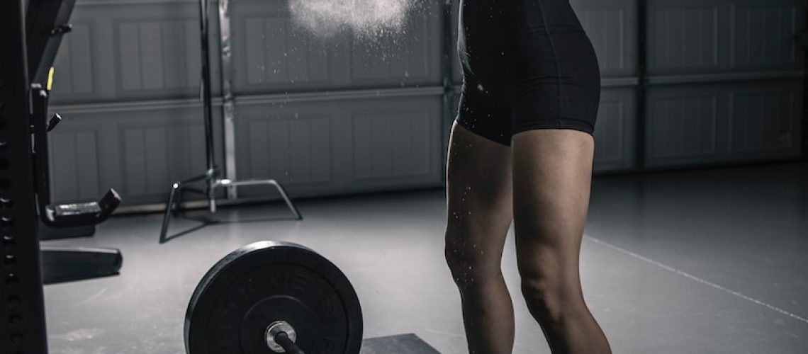 woman in black tank top and black shorts holding barbell