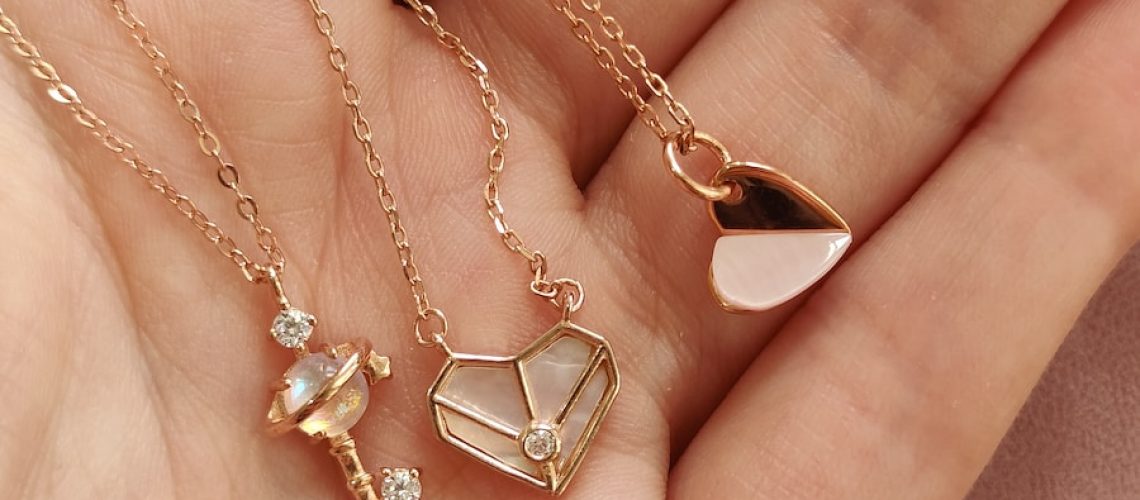 a woman's hand holding four different necklaces
